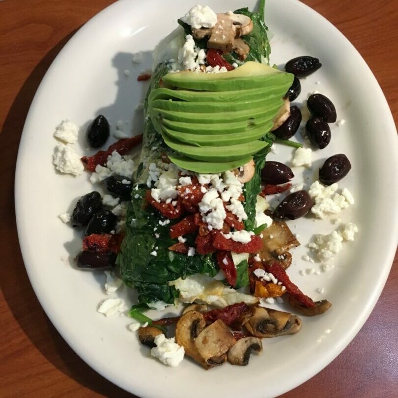 A plate of food with avocado, feta cheese and other ingredients.